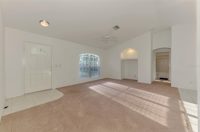 unfurnished living room featuring visible vents, ceiling fan, light colored carpet, lofted ceiling, and arched walkways