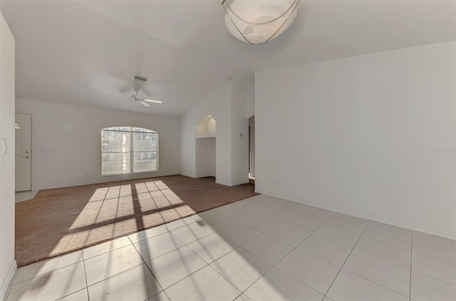 carpeted empty room with vaulted ceiling, visible vents, tile patterned floors, and ceiling fan