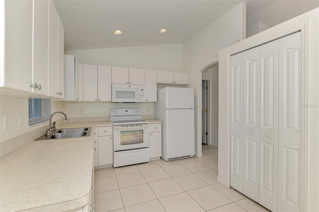 kitchen with a sink, white appliances, light countertops, light tile patterned floors, and vaulted ceiling