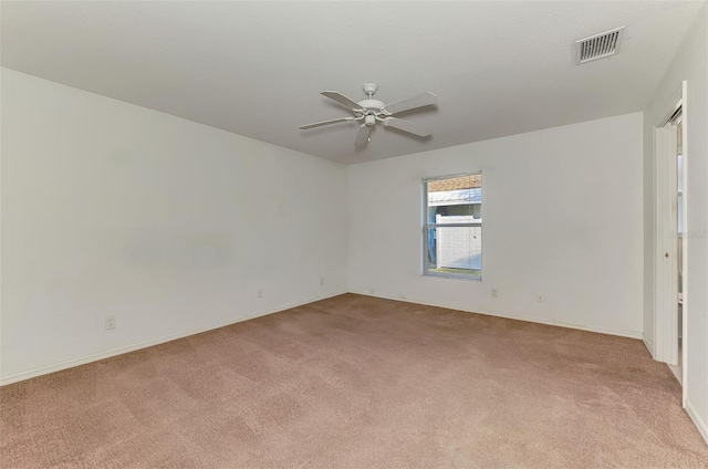 empty room with light colored carpet, a ceiling fan, and visible vents