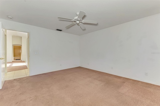 empty room featuring visible vents, light carpet, arched walkways, and a ceiling fan