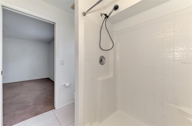 full bathroom featuring tile patterned flooring, a tile shower, toilet, and baseboards