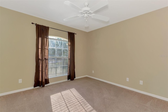 unfurnished room with a ceiling fan, baseboards, and light carpet