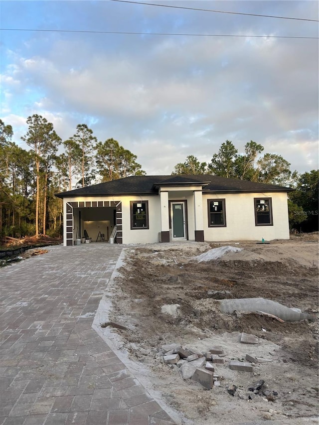 view of front of property with stucco siding, an attached garage, and decorative driveway