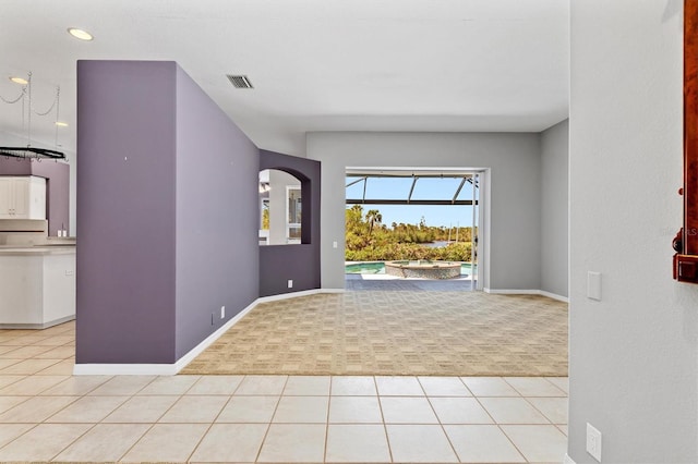 entryway featuring light tile patterned flooring, visible vents, light colored carpet, and baseboards