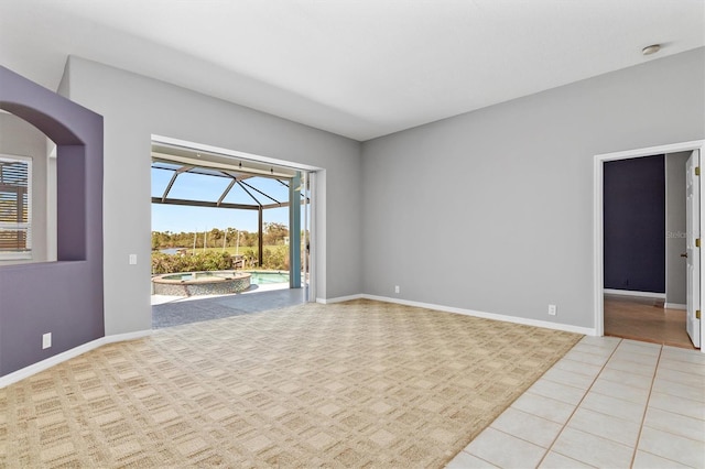 empty room with tile patterned floors, baseboards, and a sunroom