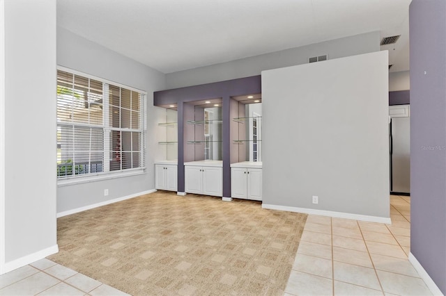 spare room featuring light tile patterned floors, visible vents, and baseboards