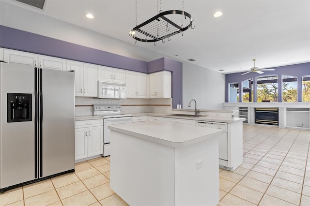 kitchen with white appliances, a kitchen island, light tile patterned flooring, a sink, and light countertops