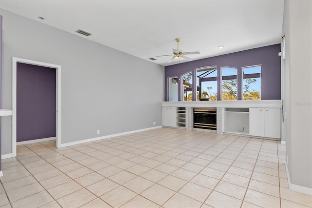 interior space with visible vents, baseboards, a ceiling fan, and a tiled fireplace