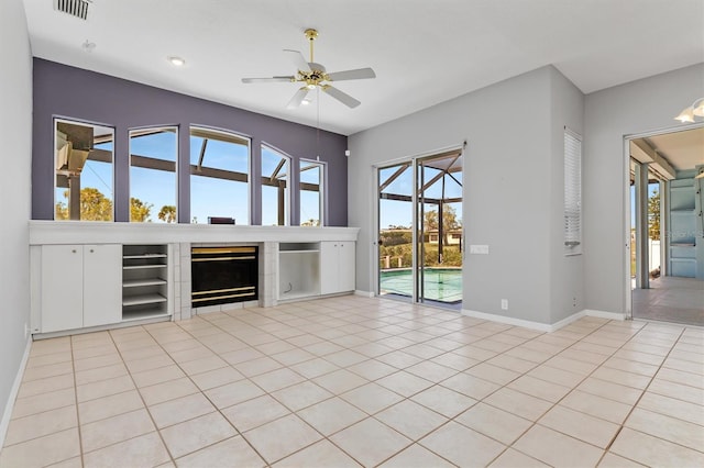 unfurnished living room featuring baseboards, visible vents, light tile patterned flooring, a fireplace, and ceiling fan