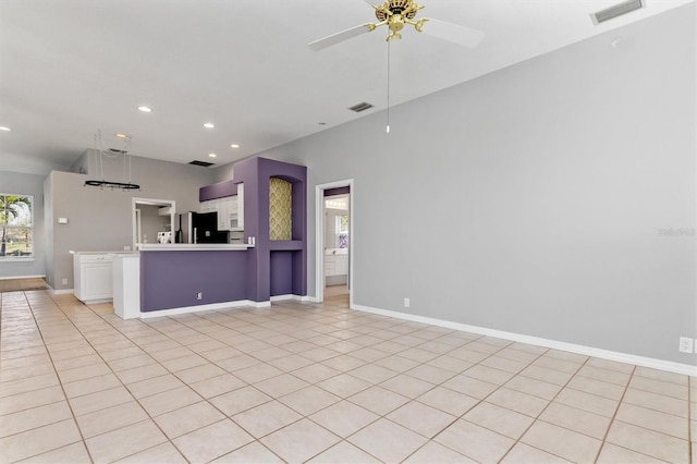 interior space with visible vents, a peninsula, freestanding refrigerator, and open floor plan