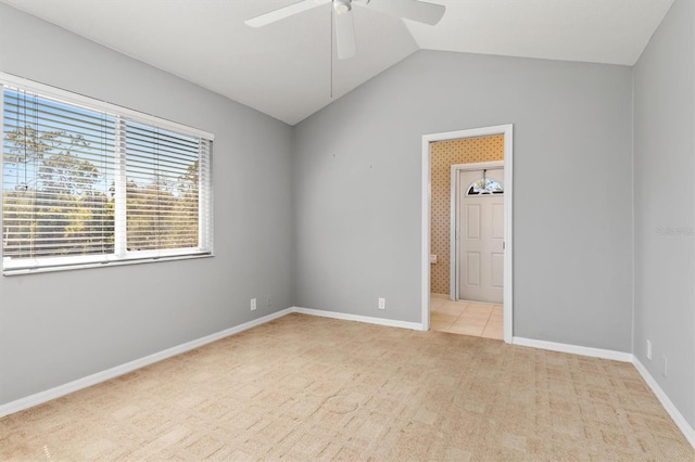 empty room featuring vaulted ceiling, light carpet, baseboards, and ceiling fan