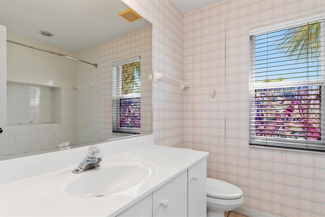 bathroom with vanity, tile walls, toilet, and visible vents