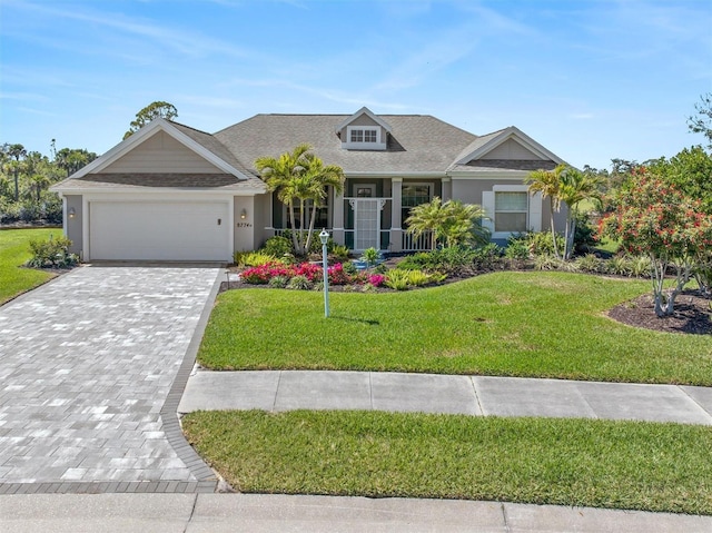 view of front of property featuring a garage, decorative driveway, a front lawn, and stucco siding