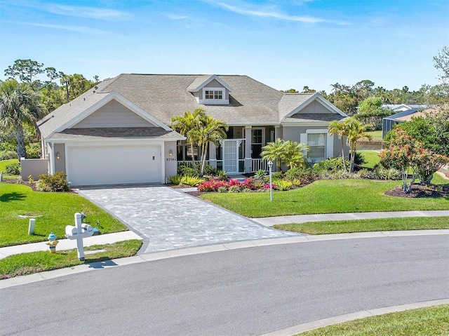 view of front of house featuring a front lawn, decorative driveway, a garage, and a shingled roof