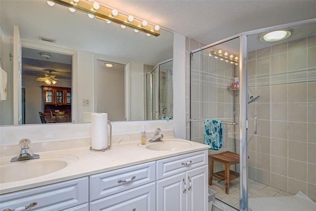 bathroom with double vanity, a stall shower, tile patterned floors, and a sink