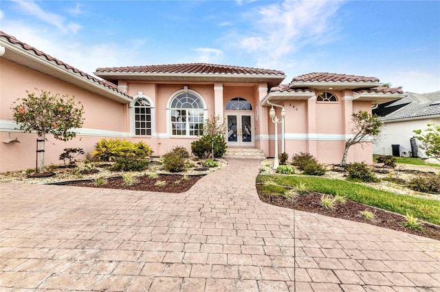 view of front of property with stucco siding, french doors, and a tile roof