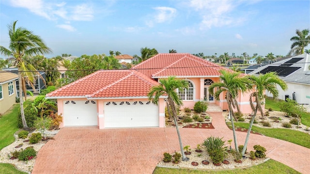 mediterranean / spanish-style home featuring a tile roof, decorative driveway, a garage, and stucco siding