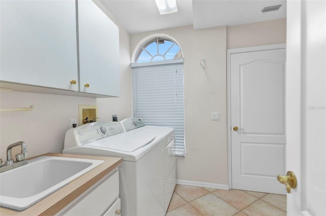 laundry area with visible vents, a sink, cabinet space, light tile patterned floors, and washing machine and clothes dryer