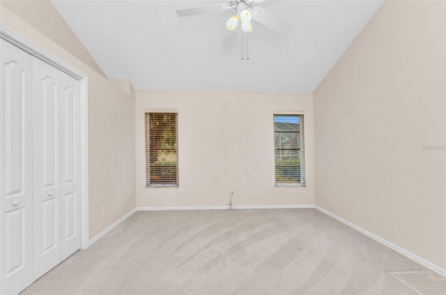 unfurnished bedroom with vaulted ceiling, light colored carpet, a closet, and baseboards