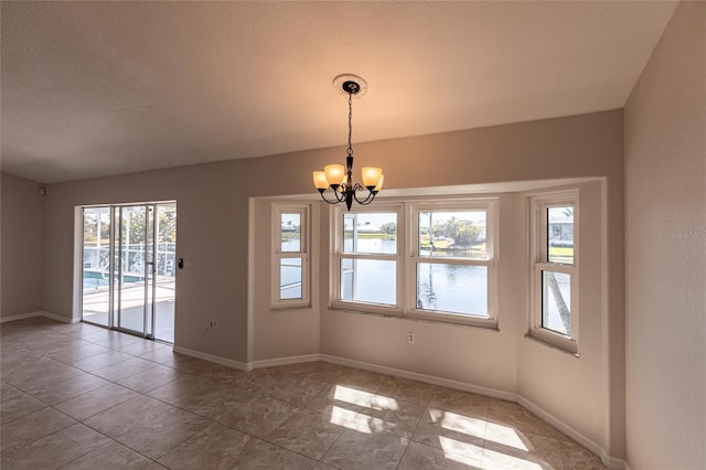 unfurnished room with an inviting chandelier, baseboards, and a textured ceiling