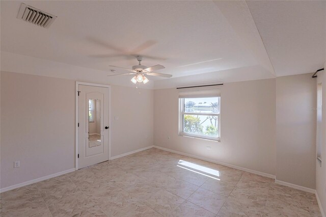 unfurnished room featuring visible vents, a ceiling fan, and baseboards