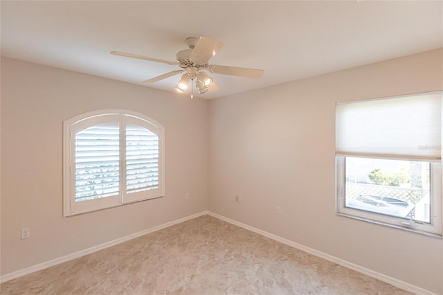 unfurnished room featuring a ceiling fan and baseboards