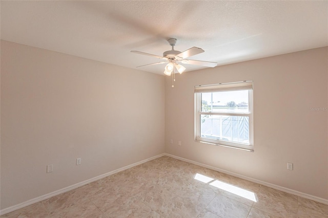 unfurnished room with ceiling fan, a textured ceiling, and baseboards