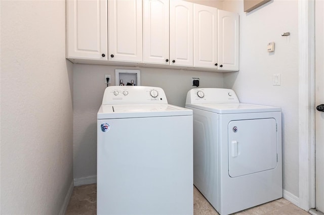 washroom featuring baseboards, cabinet space, and washing machine and clothes dryer