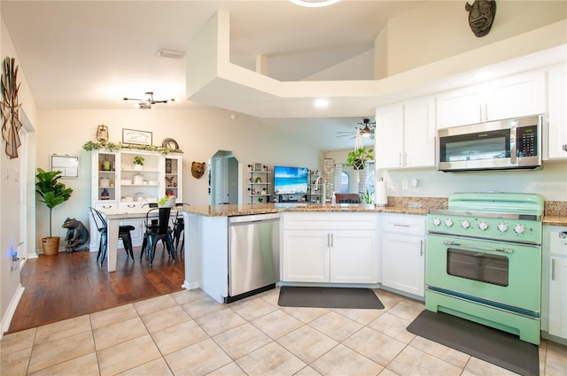 kitchen featuring white cabinetry, a peninsula, light stone countertops, and appliances with stainless steel finishes