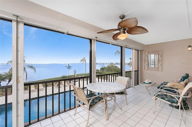 sunroom / solarium featuring ceiling fan and a water view