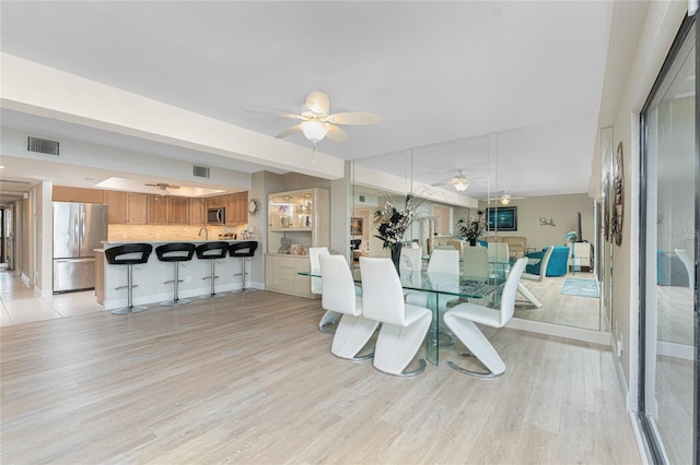 dining room with visible vents, light wood-style flooring, and a ceiling fan