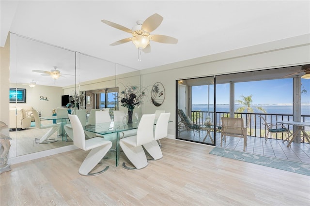 dining room with a ceiling fan, wood finished floors, and a water view