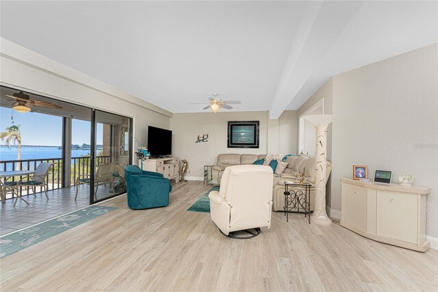 living area with light wood-style flooring, baseboards, ceiling fan, and a water view