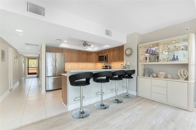 kitchen featuring visible vents, a tray ceiling, a kitchen breakfast bar, appliances with stainless steel finishes, and light countertops