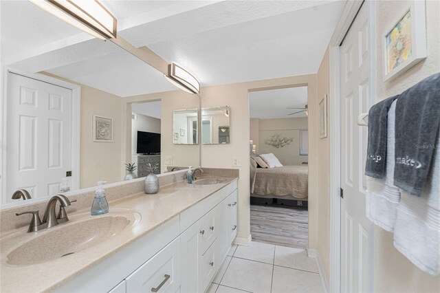 full bath featuring tile patterned flooring, ensuite bath, double vanity, and a sink