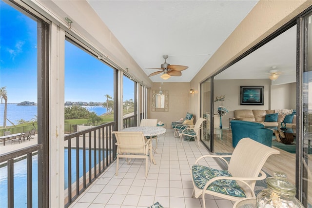 sunroom with a water view and ceiling fan