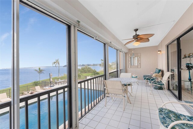 sunroom / solarium featuring ceiling fan and a water view