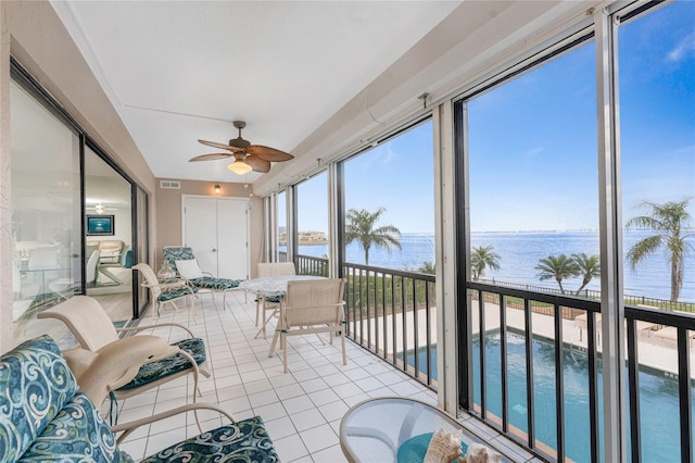 sunroom with visible vents, ceiling fan, and a water view