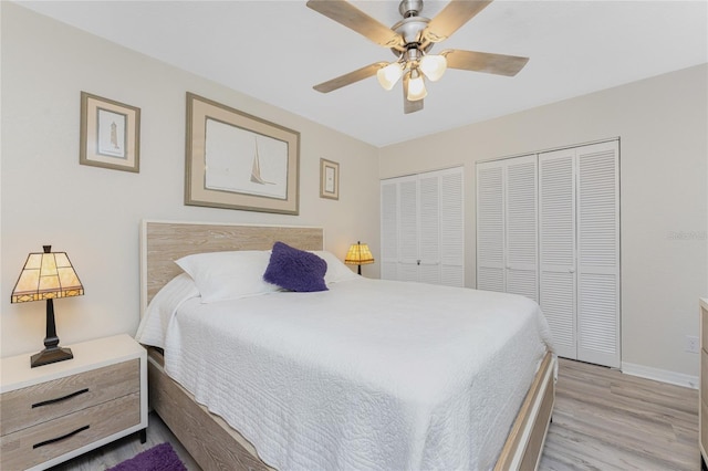 bedroom featuring baseboards, light wood-type flooring, two closets, and ceiling fan