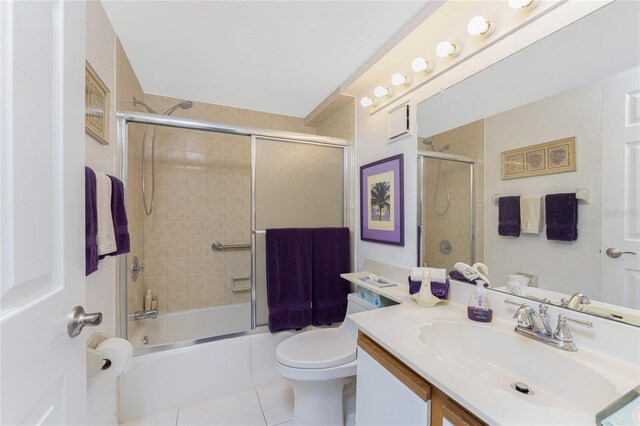 full bathroom with bath / shower combo with glass door, toilet, vanity, and tile patterned flooring