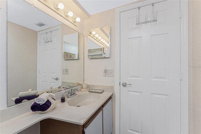 bathroom featuring visible vents, vanity, and a textured wall