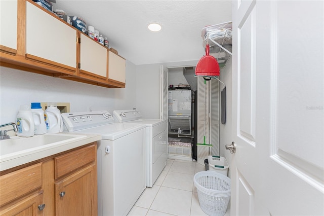 clothes washing area featuring a sink, light tile patterned flooring, cabinet space, and washer and clothes dryer