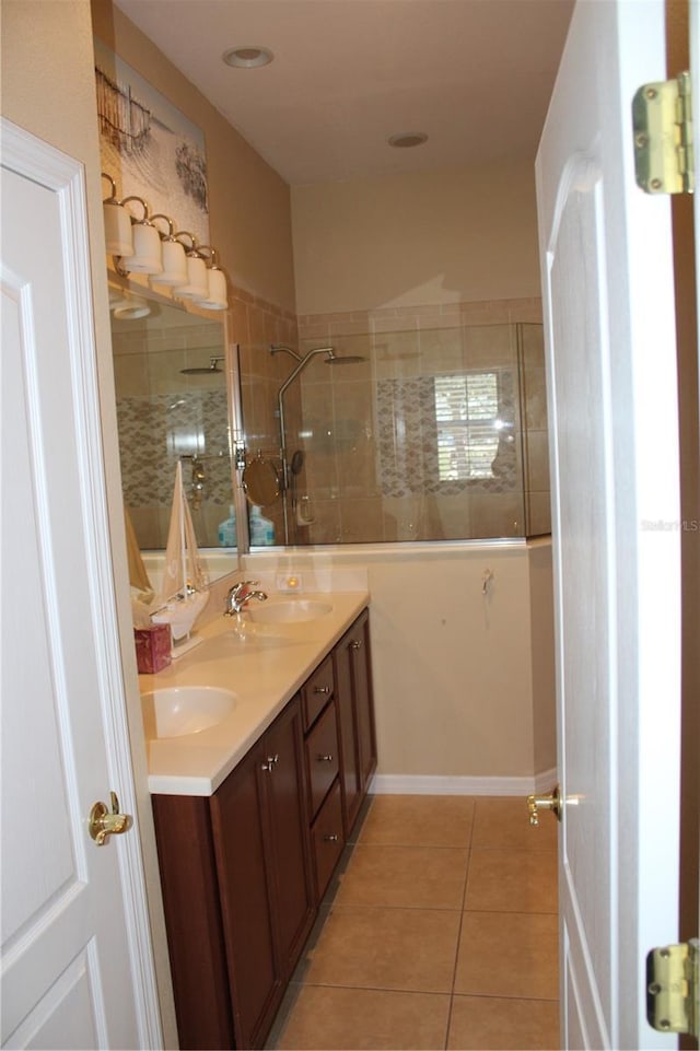 full bath featuring tile patterned flooring, double vanity, walk in shower, and a sink