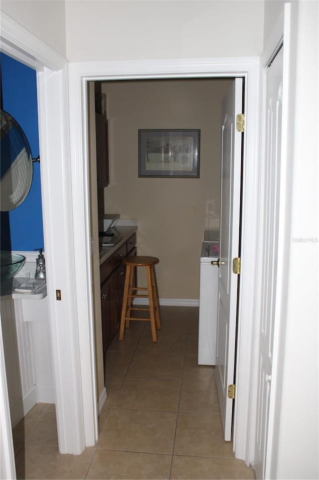 hall featuring light tile patterned floors and baseboards