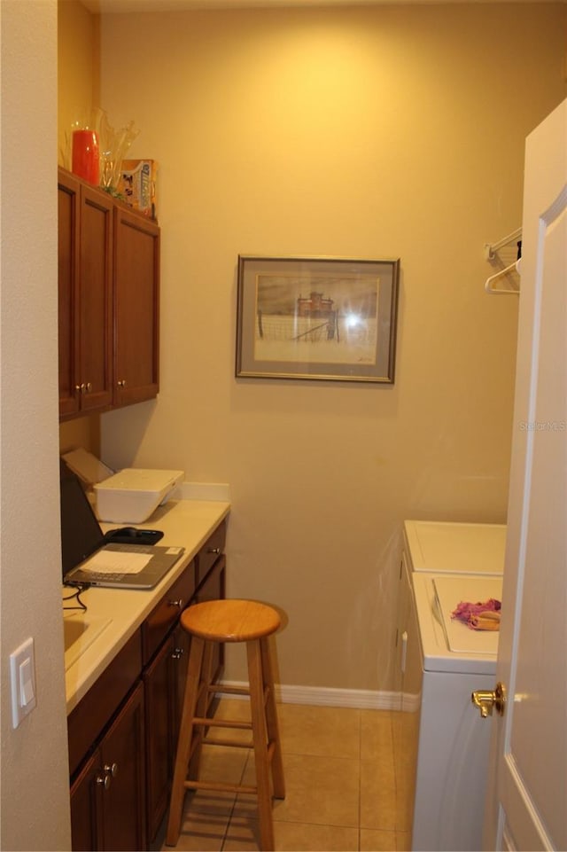 laundry area featuring baseboards, cabinet space, light tile patterned flooring, and washing machine and clothes dryer