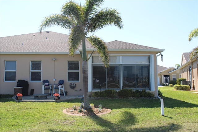 back of house featuring a shingled roof, stucco siding, a yard, a sunroom, and a patio area