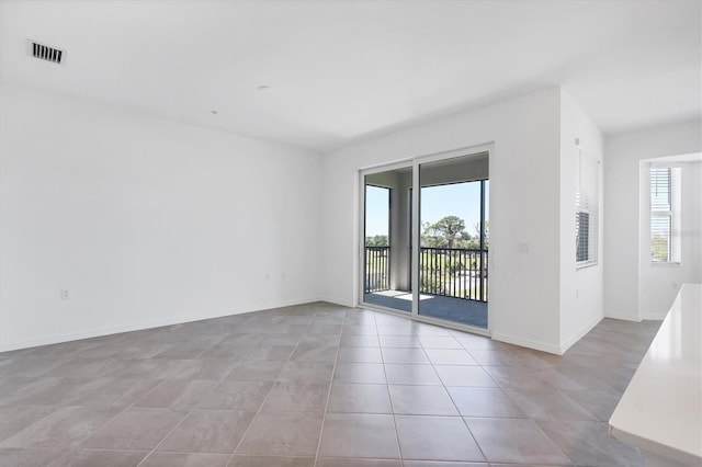 unfurnished room with light tile patterned floors, visible vents, and baseboards