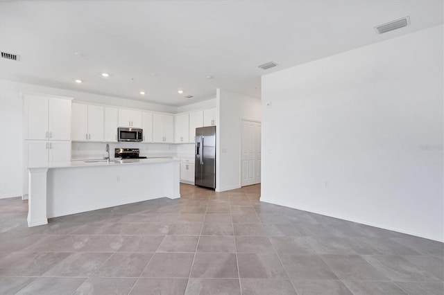 kitchen featuring visible vents, an island with sink, open floor plan, appliances with stainless steel finishes, and light countertops