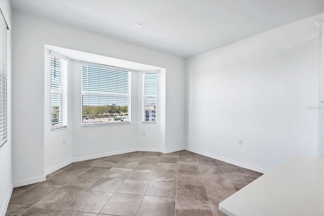 unfurnished room with tile patterned flooring and baseboards